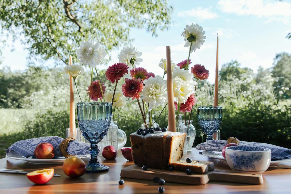 Brunch party decorations on an outside table with flowers and a cake