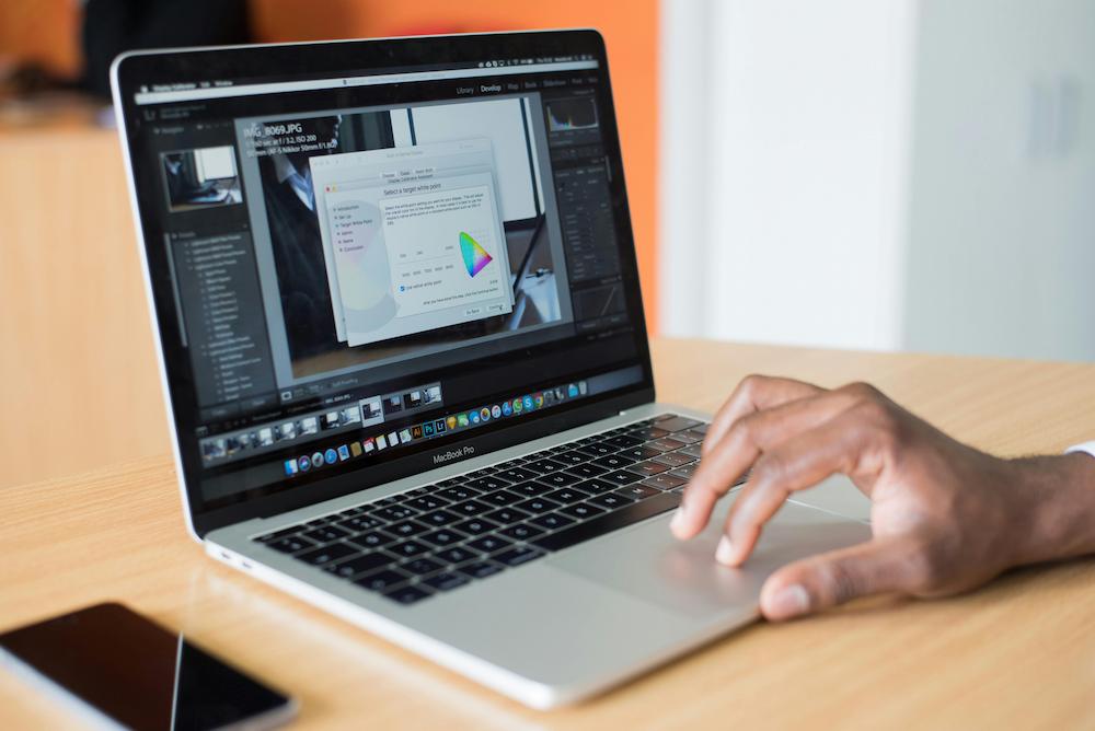 A hand on a laptop editing event photography in Lightroom