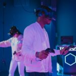 Two people in a dark space using virtual reality headsets as interactive entertainment