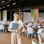 Event planner standing in a large venue room with a clipboard