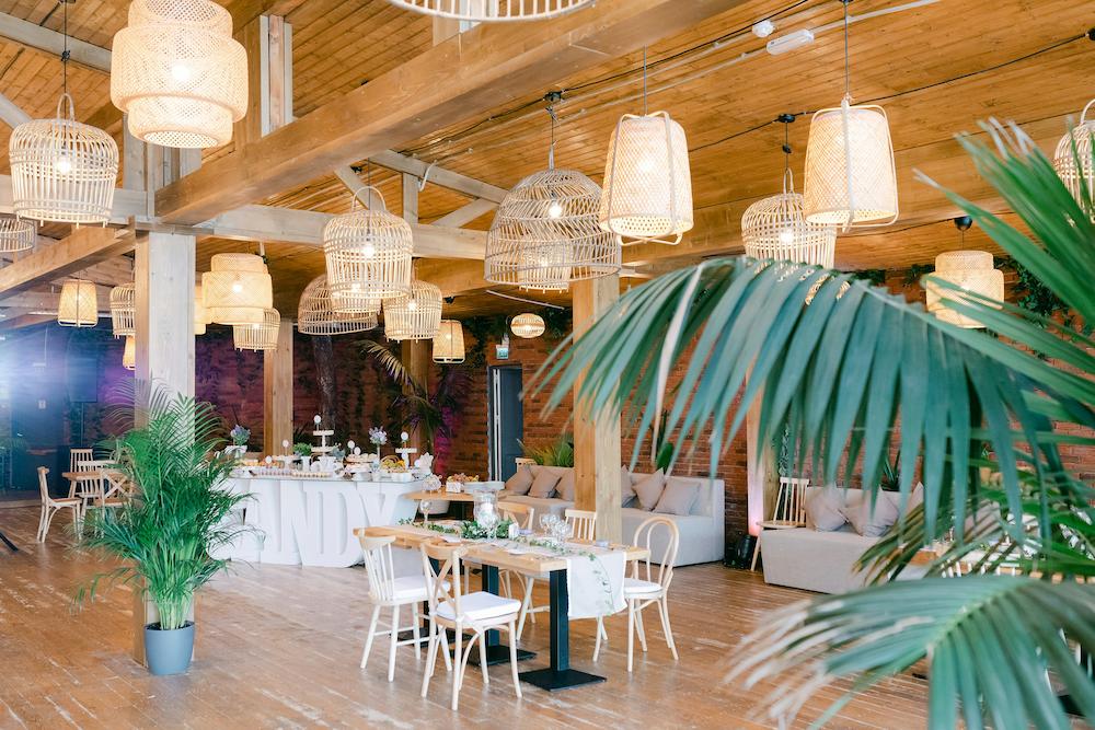 Cocktail wedding reception set up with various types of seating and a dessert buffet in neutral colours with plants