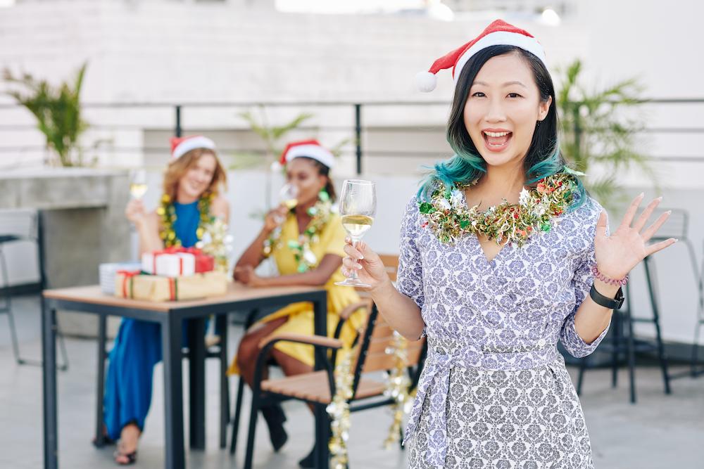 Christmas party ideas in Brisbane include rooftop bars where these three friends celebrate while wearing santa hats