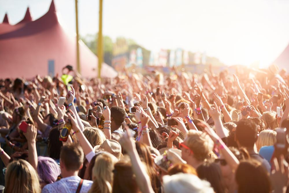 Wide shot of a festival or music outdoor events with the crowd putting their hands in the air 