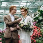 Young trendy bride and groom in a greenhouse setting with flowers surrounding them