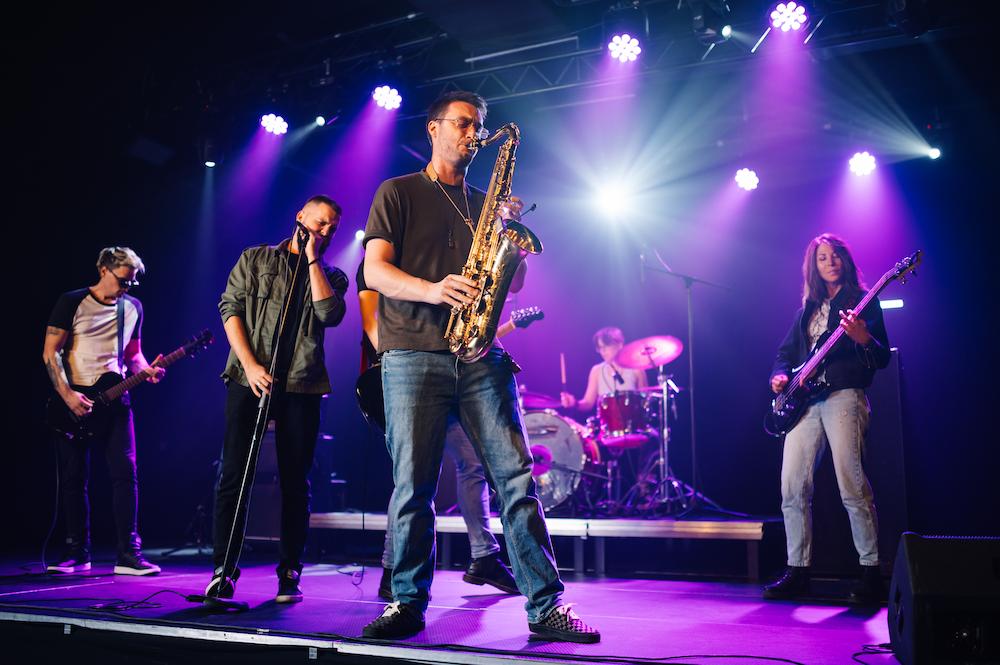 Work Christmas Party Ideas in Sydney include having a live band perform such as this band who are on a stage, playing their instruments