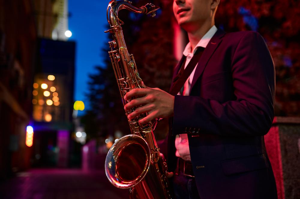 close up of a musician holding a saxaphone playing at night