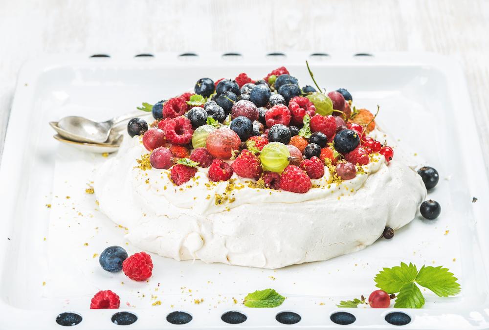 A pavlova covered with fruit that you can serve at your australia day event