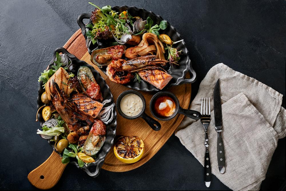 A delicious seafood platter on a wooden board with a dark background