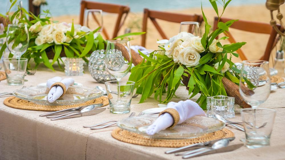 Beach wedding ideas include a reception set up like this with coastal inspired placemats and fresh greenery in the middle of the table