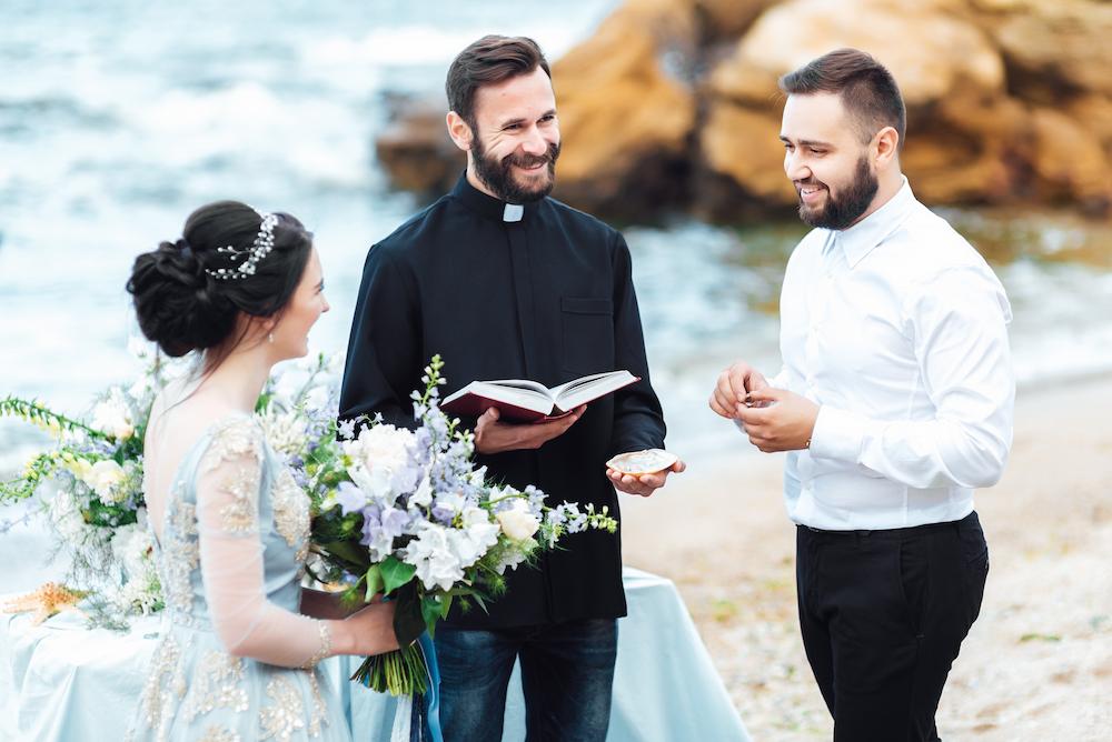 Bride and groom getting married on the beach with the bride wearing a pale blue dress which is a beach wedding idea to compliment the natural environment