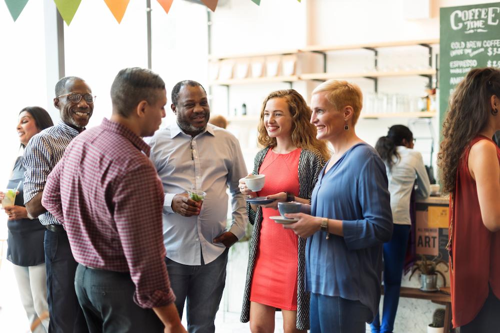 Group of men and women at a networking event holding drinks and chatting